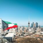 Kuwait flag waving over a city skyline with modern buildings