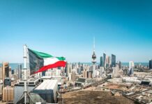 Kuwait flag waving over a city skyline with modern buildings