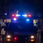Emergency vehicle with flashing lights in a busy urban area at night