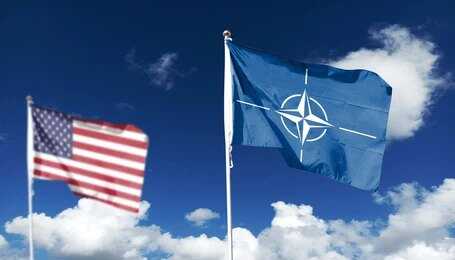 shutterstock_2625293429 Flags of various nations displayed outside NATO headquarters under a clear blue sky