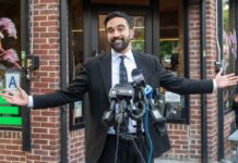 Noncitizen Voting Fight Ignites NYC Man in a suit speaking at a press conference with microphones in front of him