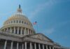 Ally at “Critical” — Capitol Charges Ahead The U.S. Capitol building with an American flag flying against a blue sky