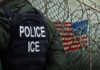 ICE Raid Exposes Identity Chaos A police officer in a tactical vest stands near a barbed wire fence with an American flag in the background