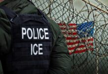 ICE Raid Exposes Identity Chaos A police officer in a tactical vest stands near a barbed wire fence with an American flag in the background