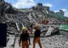 Person walking past rubble and destroyed buildings on a dirt road