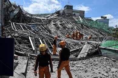 shutterstock_2794925219 Person walking past rubble and destroyed buildings on a dirt road