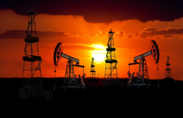 Oil,Field,At,Sunset. Silhouetted oil rigs against a vibrant sunset