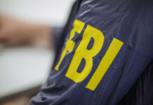 FBI Raid, Iran Ties—CEO in Cuffs Close-up of an FBI agents jacket with yellow lettering