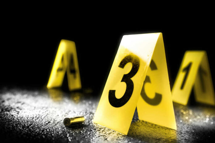 shutterstock_733909831 Yellow evidence markers with numbers at a crime scene alongside a bullet casing