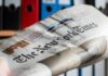 Newspaper held in hand with office binders in the background