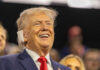 Butler Bullet Question Finally Answered A smiling man in a suit at a political rally, engaging with the audience