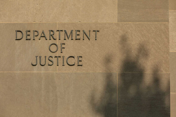 shutterstock2557865709jpg-1 Sign reading Department of Justice on a stone wall with a shadow