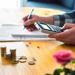 person using calculator with coins on table