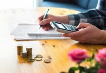 American Dream Blocked At The Front Door person using calculator with coins on table