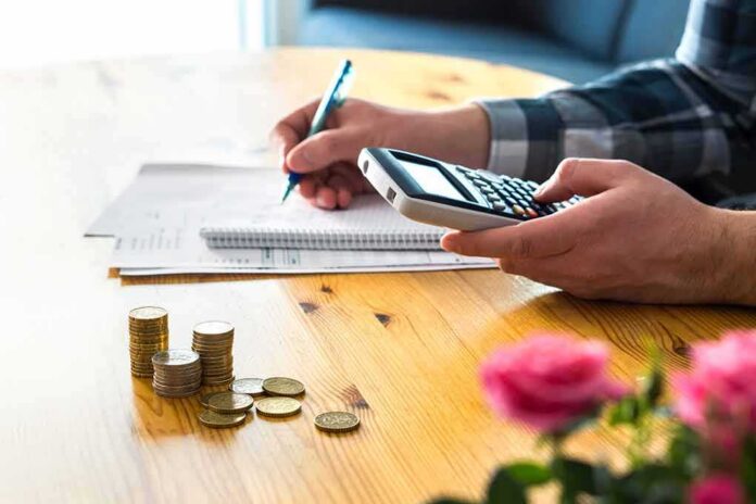 person using calculator with coins on table
