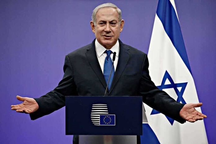 shutterstock_1046491414-1 man in suit speaking at a podium with Israeli flag