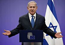 Colombia’s New Leader Sides With Israel man in suit speaking at a podium with Israeli flag