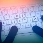 Software Meltdown Warps NJ Elections Gloved hands typing on a keyboard with highlighted election keys