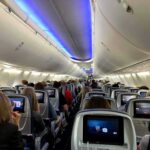 Airplane cabin with passengers seated and seatback screens