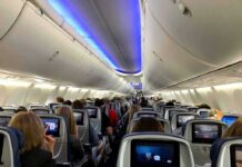 Airplane cabin with passengers seated and seatback screens