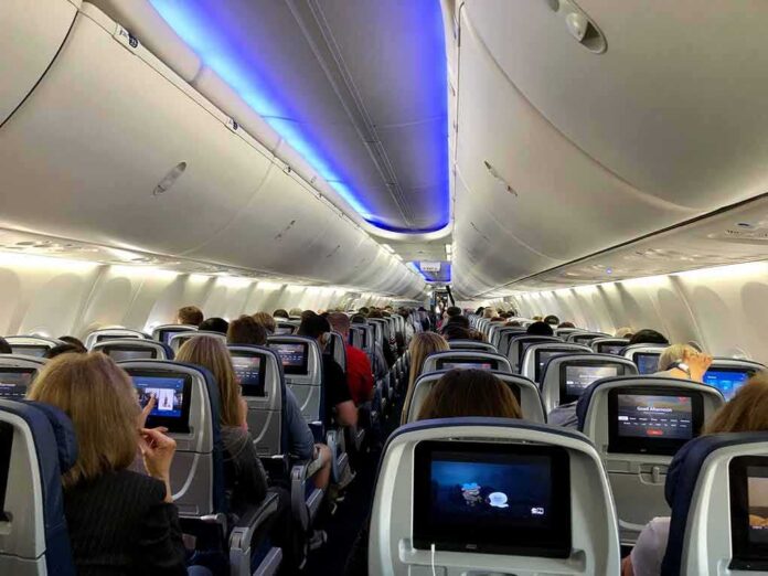 Airplane cabin with passengers seated and seatback screens