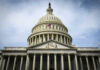Congress Weighs $1.5T Defense Plan The U.S. Capitol building with an American flag flying in front