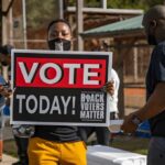 Michigan Senator’s Secret Vote Claim Person holding a large voting sign at an outdoor event