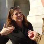 Woman being interviewed outside a stone building