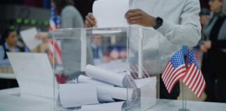 Person casting a vote into a transparent ballot box during an election