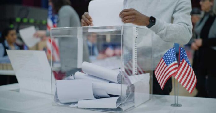 Close,Up,Shot,Of,Polling,Box,Standing,On,Table,In Person casting a vote into a transparent ballot box during an election