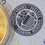 Inside Warsh’s First Fed Meeting Close-up of a gold coin next to a US dollar bill