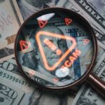 Magnifying glass over U.S. dollar bills with a scam warning