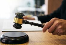 Judge Rejects Bid Over Secret Evidence Deal Judge's hand holding a gavel over a sound block