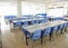 Donor-Driven Dollars Reshape Classrooms Empty cafeteria with rows of blue chairs and long tables
