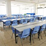 Donor-Driven Dollars Reshape Classrooms Empty cafeteria with rows of blue chairs and long tables