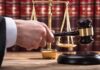Killer Cadillac Mystery Grips Tupac Trial Judge's hand holding gavel near scales of justice
