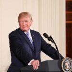 Trump’s DOJ Overhaul Sparks Independence Fight man at podium with presidential seal
