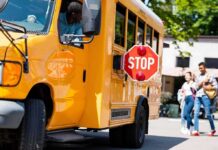 School bus with extended stop sign near students on sidewalk