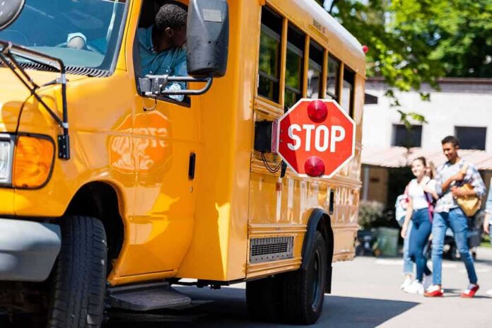 School bus with extended stop sign near students on sidewalk