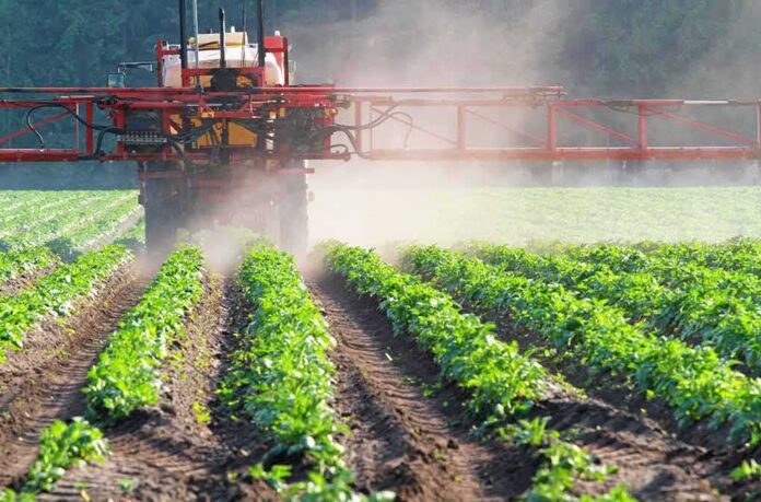 shutterstock_1168537846 Crop sprayer applies mist over green rows of plants