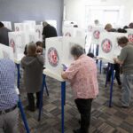 Federal Case Uncovers A Shocking Voting Twist Voters fill out ballots at polling booths in a busy voting room