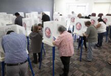 Federal Case Uncovers A Shocking Voting Twist Voters fill out ballots at polling booths in a busy voting room