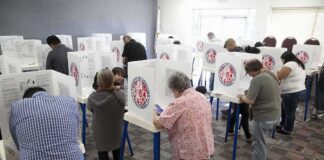 Voters fill out ballots at polling booths in a busy voting room