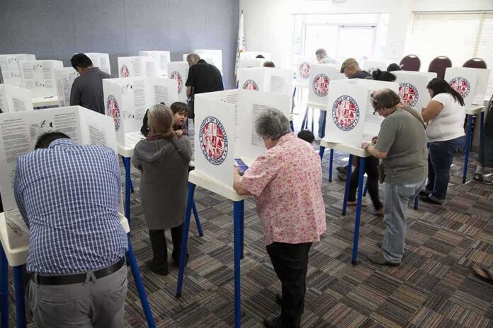 Voters fill out ballots at polling booths in a busy voting room