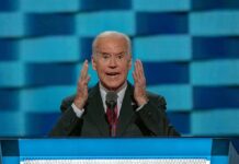 elderly man in suit speaking at a podium