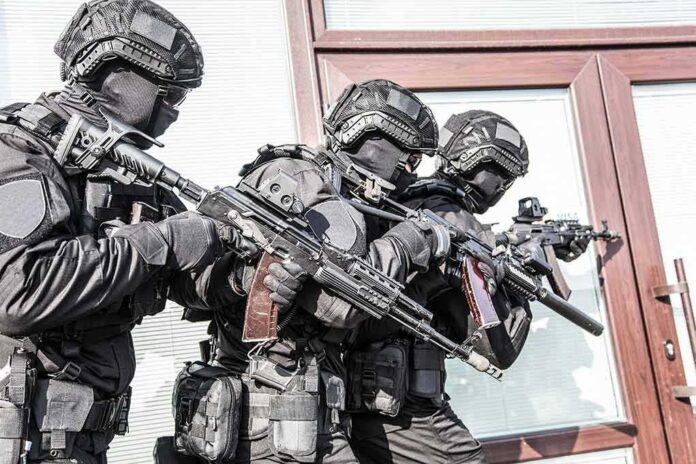 shutterstock_1391041331 Tactical officers in black gear stack up with rifles by a building