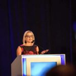 New Filing Brings Former Senator Into Spotlight Woman speaking at a podium on a stage