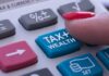 Silicon Valley Showdown Over Billionaire Tax finger pressing tax button on calculator