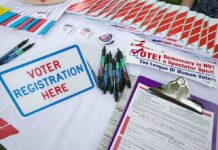 Ballot Brawl Explodes Over SAVE Act Voter registration table with forms, pens, and informational materials