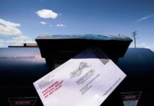 Election Shake-Up Paused After Court Rebuke Mail-in ballot being inserted into a blue USPS mailbox